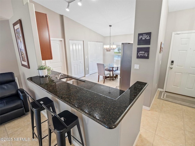 kitchen with a breakfast bar, pendant lighting, stainless steel refrigerator, sink, and kitchen peninsula