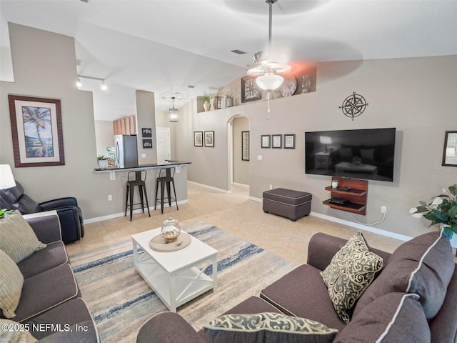 living room with ceiling fan, lofted ceiling, rail lighting, and light tile patterned floors