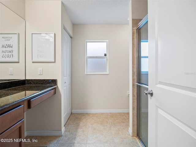 bathroom with a shower with door, vanity, tile patterned floors, and a textured ceiling