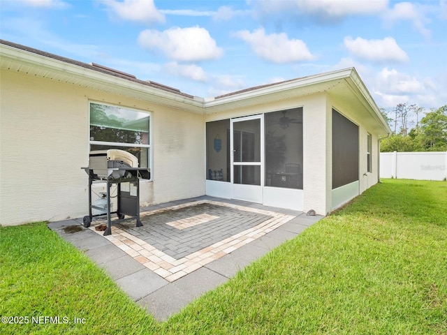 rear view of house featuring a patio, a sunroom, and a lawn