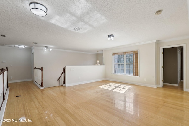 empty room with crown molding, light hardwood / wood-style flooring, and a textured ceiling