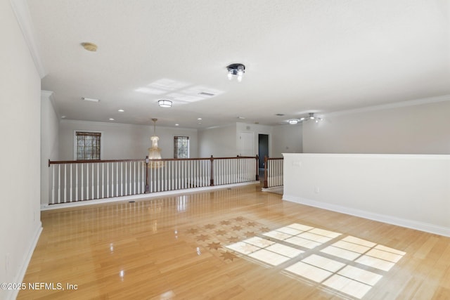 empty room with ornamental molding and light hardwood / wood-style flooring