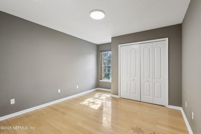 unfurnished bedroom with a closet, light hardwood / wood-style flooring, and a textured ceiling