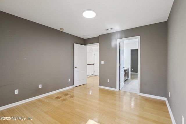 unfurnished bedroom with ensuite bath and light wood-type flooring