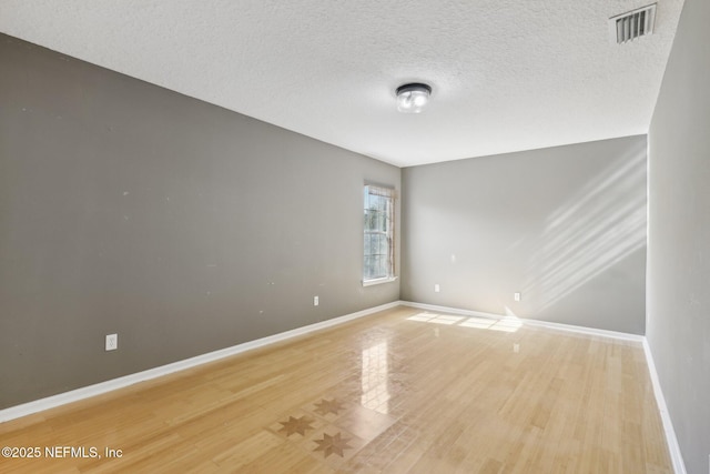 spare room featuring hardwood / wood-style floors and a textured ceiling