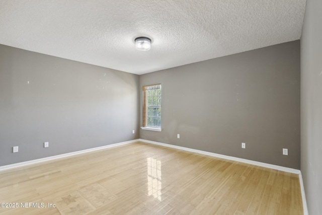 empty room featuring a textured ceiling and light hardwood / wood-style flooring