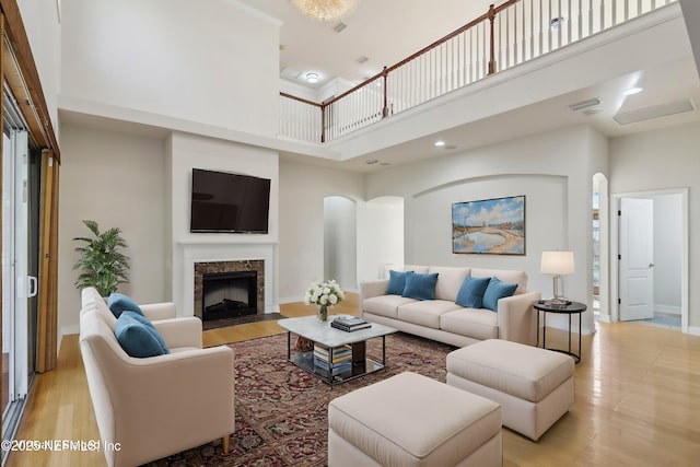 living room featuring a high ceiling, a premium fireplace, and light hardwood / wood-style flooring