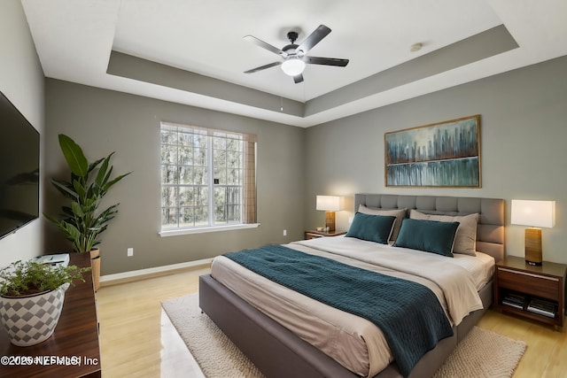 bedroom featuring a tray ceiling, light hardwood / wood-style flooring, and ceiling fan