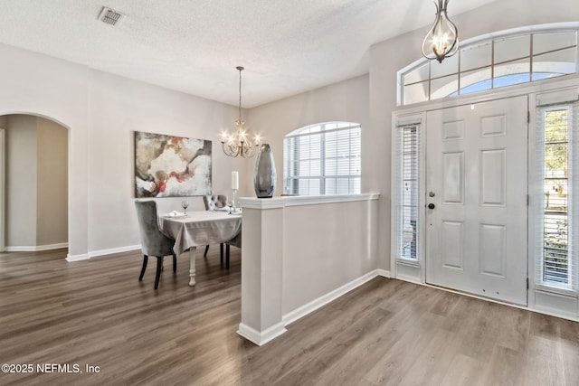 entryway with an inviting chandelier, wood-type flooring, and a textured ceiling