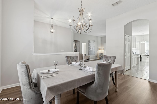 dining space with an inviting chandelier and dark hardwood / wood-style flooring