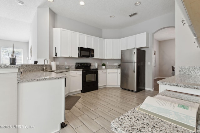 kitchen with white cabinetry, sink, black appliances, light stone countertops, and a textured ceiling