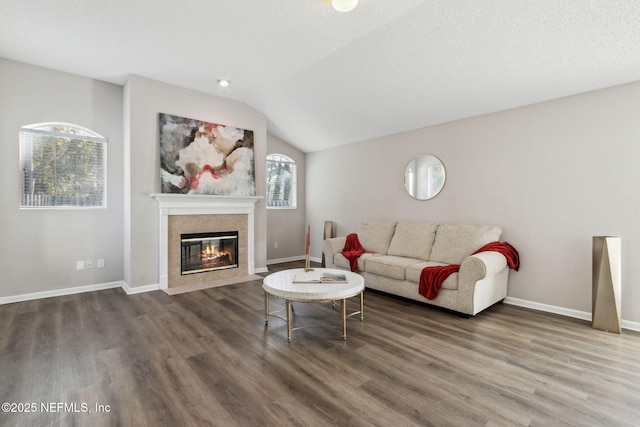 living room featuring vaulted ceiling, dark hardwood / wood-style floors, a textured ceiling, and a fireplace