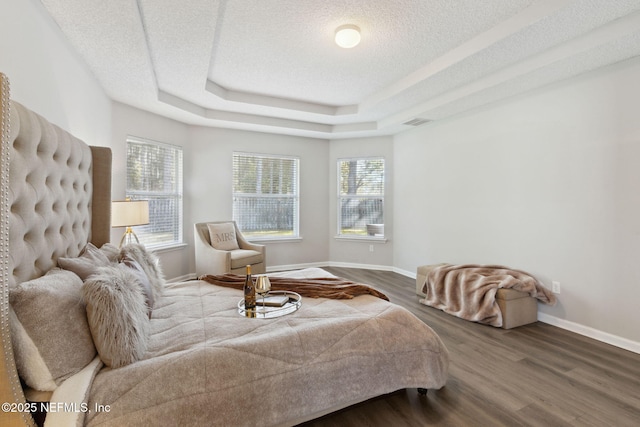 bedroom featuring hardwood / wood-style flooring, a tray ceiling, and a textured ceiling