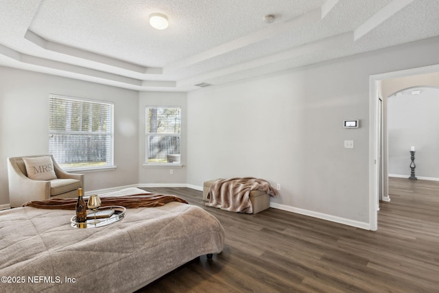 bedroom with dark hardwood / wood-style floors, a textured ceiling, and a tray ceiling