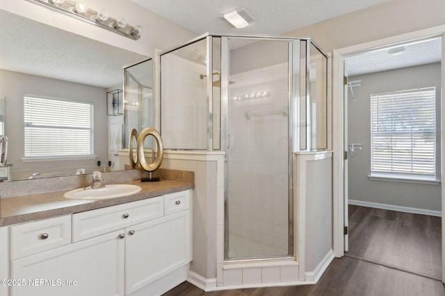 bathroom featuring vanity, hardwood / wood-style flooring, a shower with shower door, and a textured ceiling