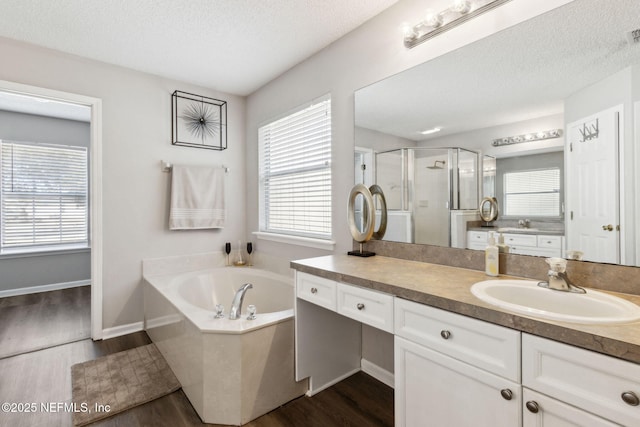 bathroom with hardwood / wood-style flooring, vanity, shower with separate bathtub, and a textured ceiling