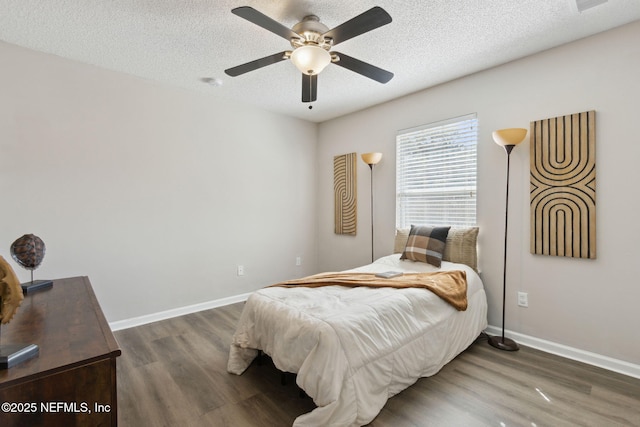 bedroom with ceiling fan, dark wood-type flooring, and a textured ceiling