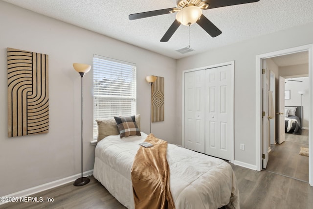 bedroom with ceiling fan, a closet, dark hardwood / wood-style floors, and a textured ceiling