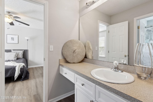 bathroom with vanity, ceiling fan, wood-type flooring, and a textured ceiling