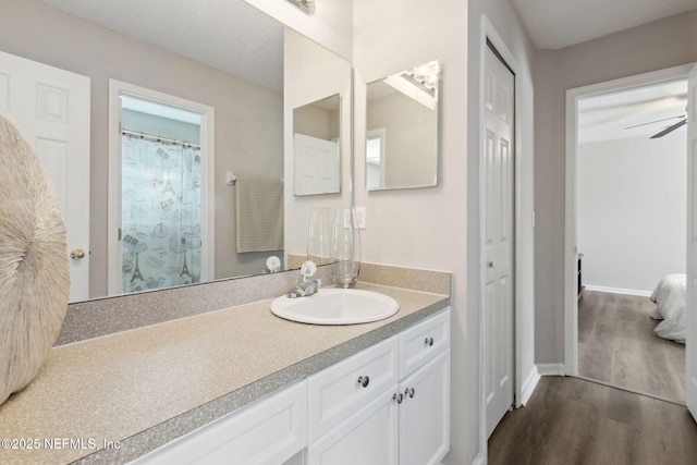 bathroom with vanity, wood-type flooring, a textured ceiling, and ceiling fan