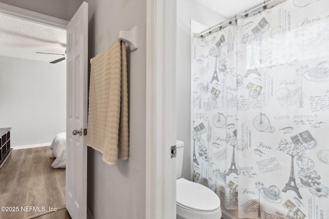 bathroom with hardwood / wood-style floors, shower / tub combo, ceiling fan, toilet, and a textured ceiling