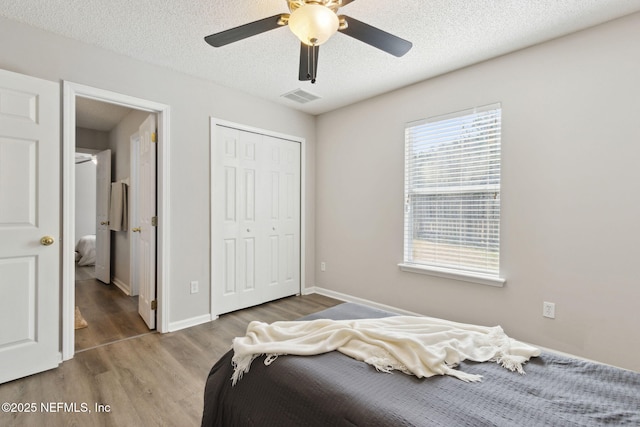 bedroom with ceiling fan, wood-type flooring, a closet, and a textured ceiling