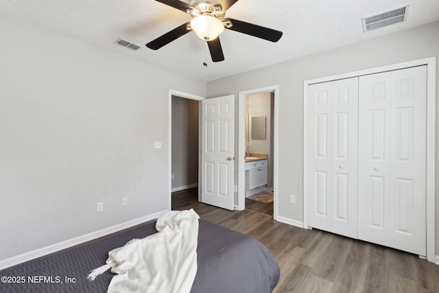 bedroom featuring connected bathroom, ceiling fan, dark wood-type flooring, a textured ceiling, and a closet