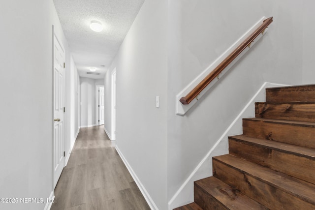 hallway with light hardwood / wood-style flooring and a textured ceiling