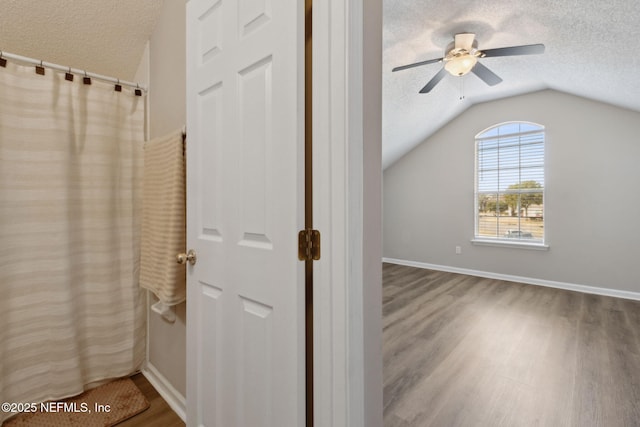 bathroom with hardwood / wood-style flooring, ceiling fan, vaulted ceiling, and a textured ceiling