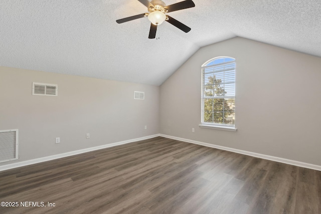 additional living space featuring ceiling fan, vaulted ceiling, dark hardwood / wood-style floors, and a textured ceiling