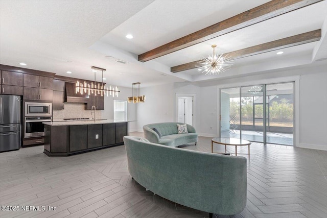 living room with beam ceiling, sink, a chandelier, and light parquet floors