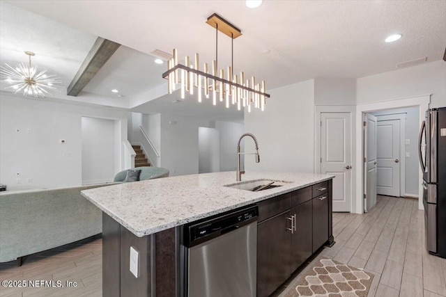 kitchen featuring sink, a kitchen island with sink, stainless steel appliances, and decorative light fixtures