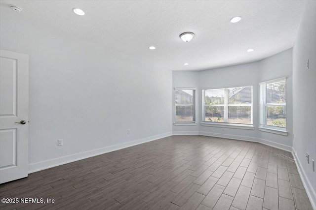 empty room featuring a textured ceiling and dark hardwood / wood-style flooring