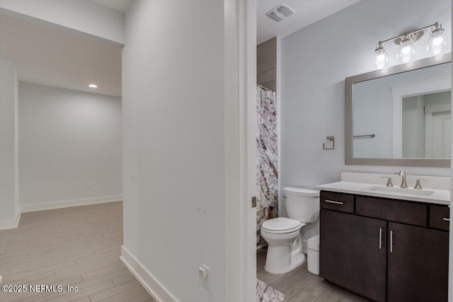 bathroom with hardwood / wood-style flooring, toilet, and vanity