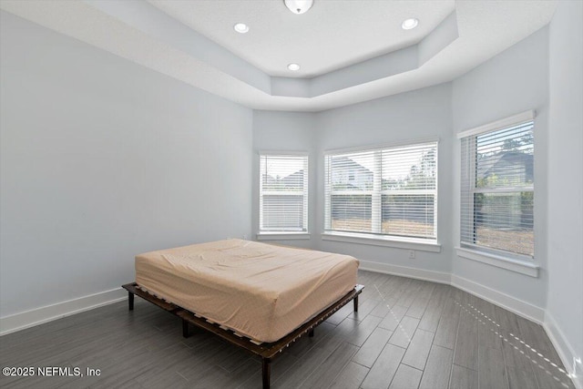 bedroom with a tray ceiling and dark wood-type flooring