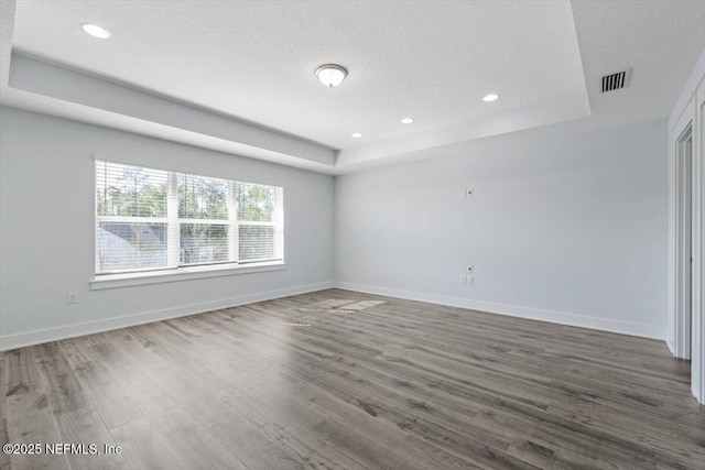 spare room featuring a tray ceiling, a textured ceiling, and hardwood / wood-style flooring