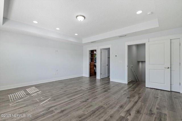 unfurnished bedroom with hardwood / wood-style floors, a closet, a tray ceiling, and a textured ceiling