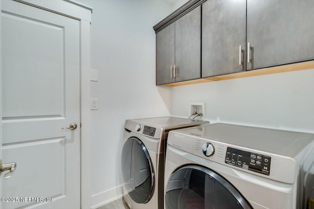 clothes washing area featuring cabinets and washing machine and clothes dryer