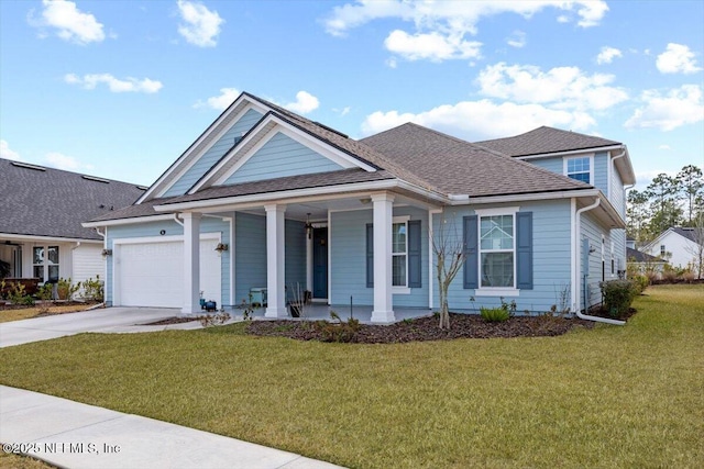 view of front of home featuring covered porch, a garage, and a front lawn