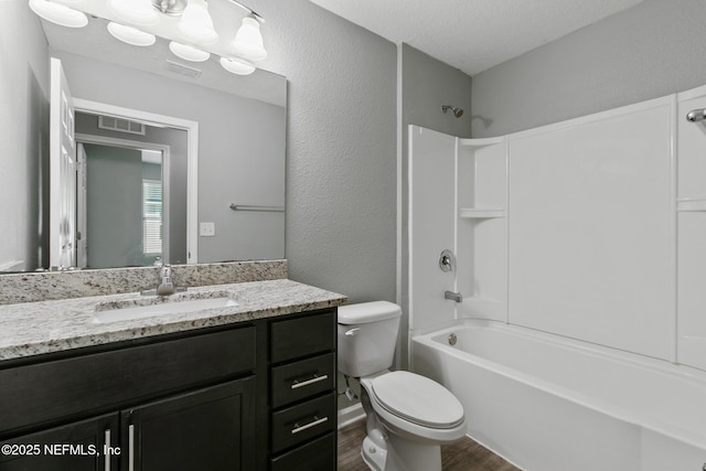 full bathroom featuring  shower combination, hardwood / wood-style floors, vanity, a textured ceiling, and toilet