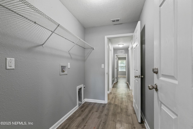 laundry room featuring dark hardwood / wood-style flooring, hookup for a washing machine, electric dryer hookup, and a textured ceiling