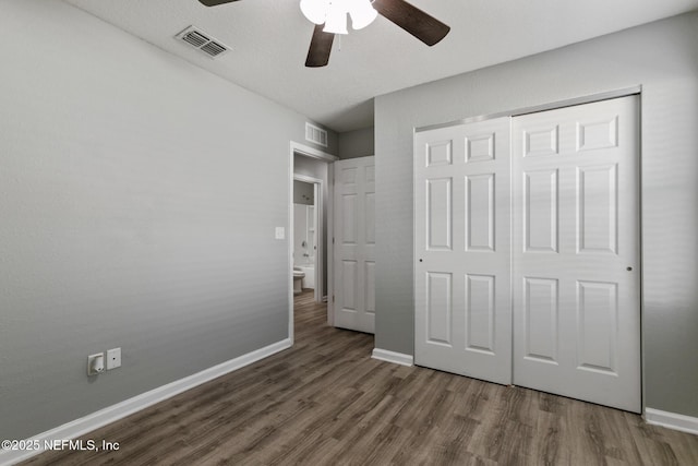 unfurnished bedroom featuring dark hardwood / wood-style flooring, a closet, and ceiling fan