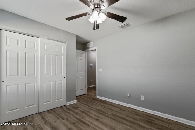 unfurnished bedroom with ceiling fan, dark hardwood / wood-style flooring, a closet, and a textured ceiling