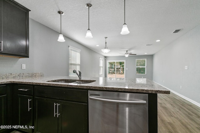 kitchen with hardwood / wood-style floors, decorative light fixtures, sink, stainless steel dishwasher, and light stone counters