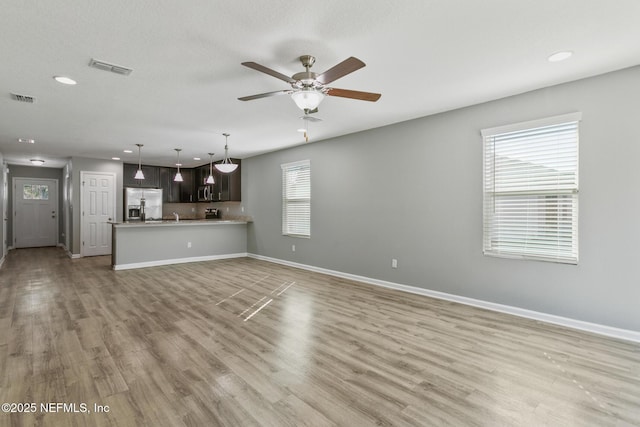 unfurnished living room featuring ceiling fan and light wood-type flooring