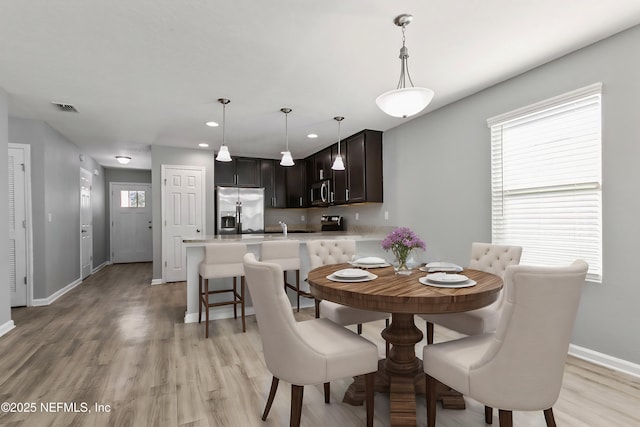 dining area with sink and light wood-type flooring