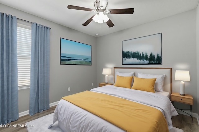 bedroom featuring ceiling fan, multiple windows, and light hardwood / wood-style flooring