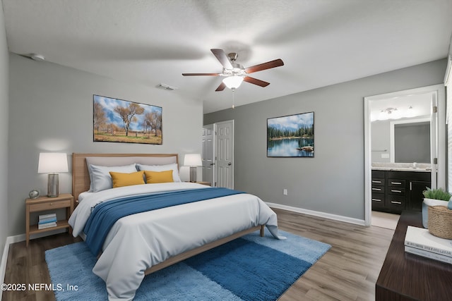 bedroom featuring hardwood / wood-style flooring, ensuite bathroom, sink, and ceiling fan