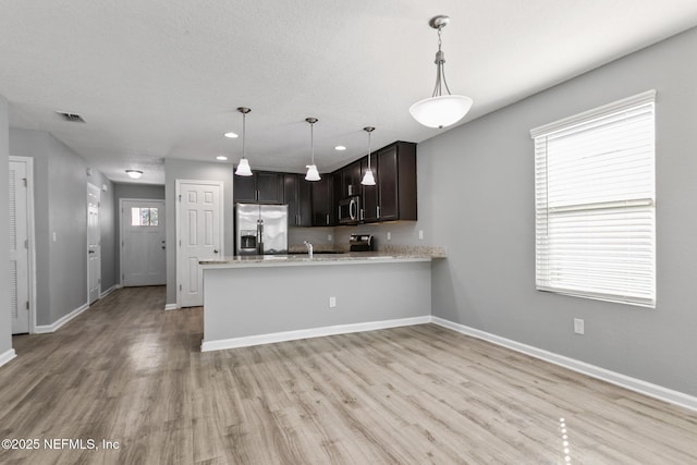 kitchen with dark brown cabinetry, light hardwood / wood-style floors, kitchen peninsula, and appliances with stainless steel finishes