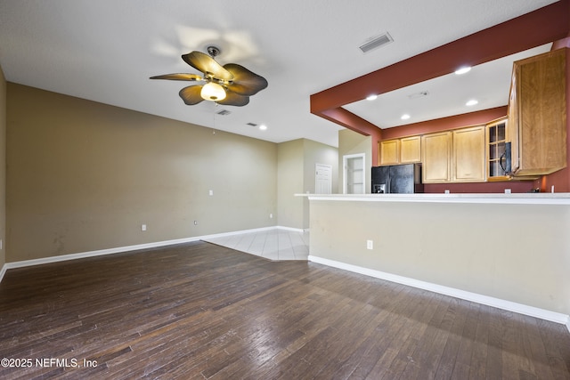 kitchen featuring black fridge, ceiling fan, and wood-type flooring